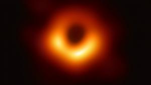 Abbildung eines schwarzen Lochs. Der Hintergrund des Bildes ist schwarz, in der Mitte ist ein rot-orangener Lichtring zu erkennen, der wiederum einen schwarzen Kreis in der Mitte hat.