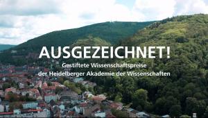 Titelbild des Ausgezeichnet-Film, Heidelberger Altstadt aus der Vogelperspektive, links die Stadt, rechts der Königstuhl. Im Vordergrund über dem Bild in weißer Schrift "AUSGEZEICHNET!" darunter kleiner "Gestiftete Wissenschaftspreise der Heidelberger Akademie der Wissenschaften"